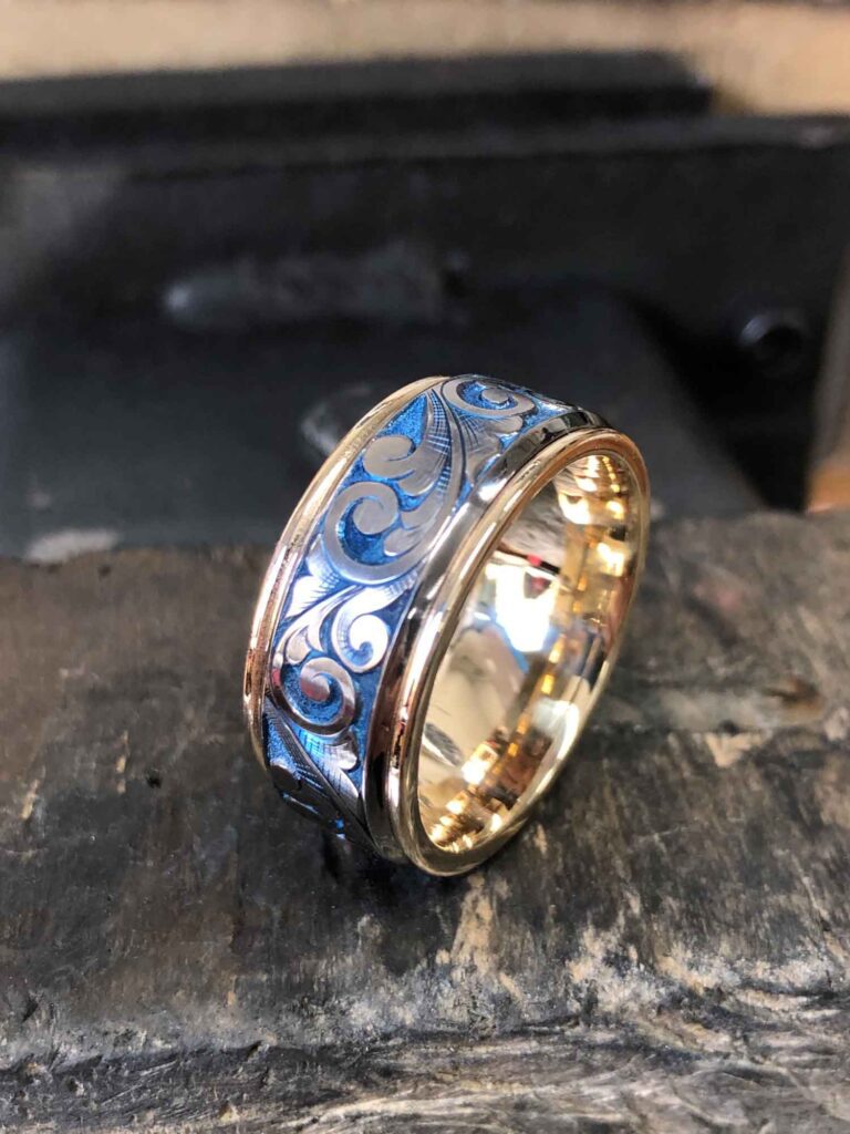 High-polish round gold ring placed upright on a wooden table, featuring a unique pattern on the band.