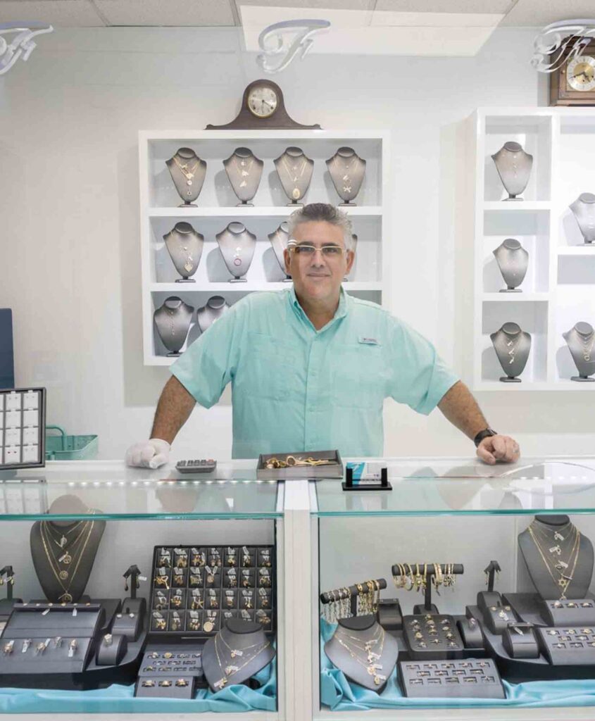 Misael in jewelry corner, surrounded by glass cabinets displaying jewelry and mannequins.