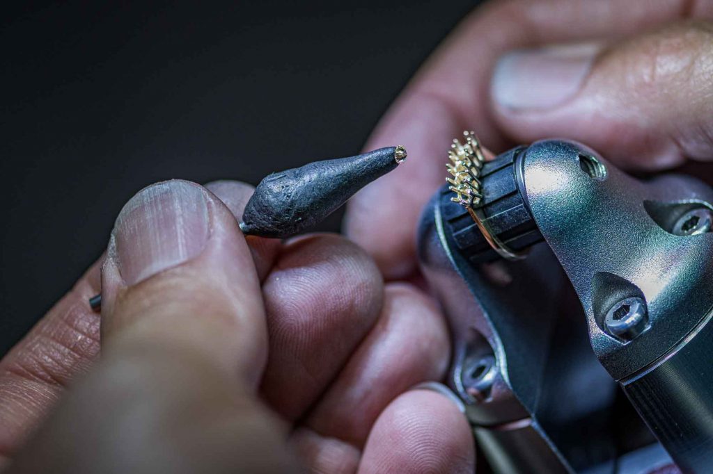Jewelry technician holding a ring holder, carefully positions a piece of gem onto the ring.